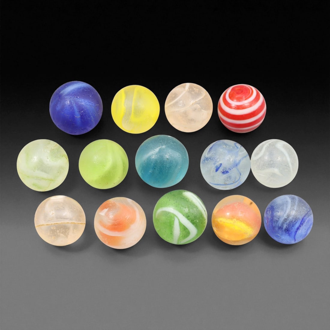 Vintage Glass Marbles Lot, Mid-20th Century, 1.5-1.7cm: This charming lot of vintage glass marbles, dating from the mid-20th century, reflects the artistry and playfulness of early handmade and molded glass craftsmanship. These marbles were produced during