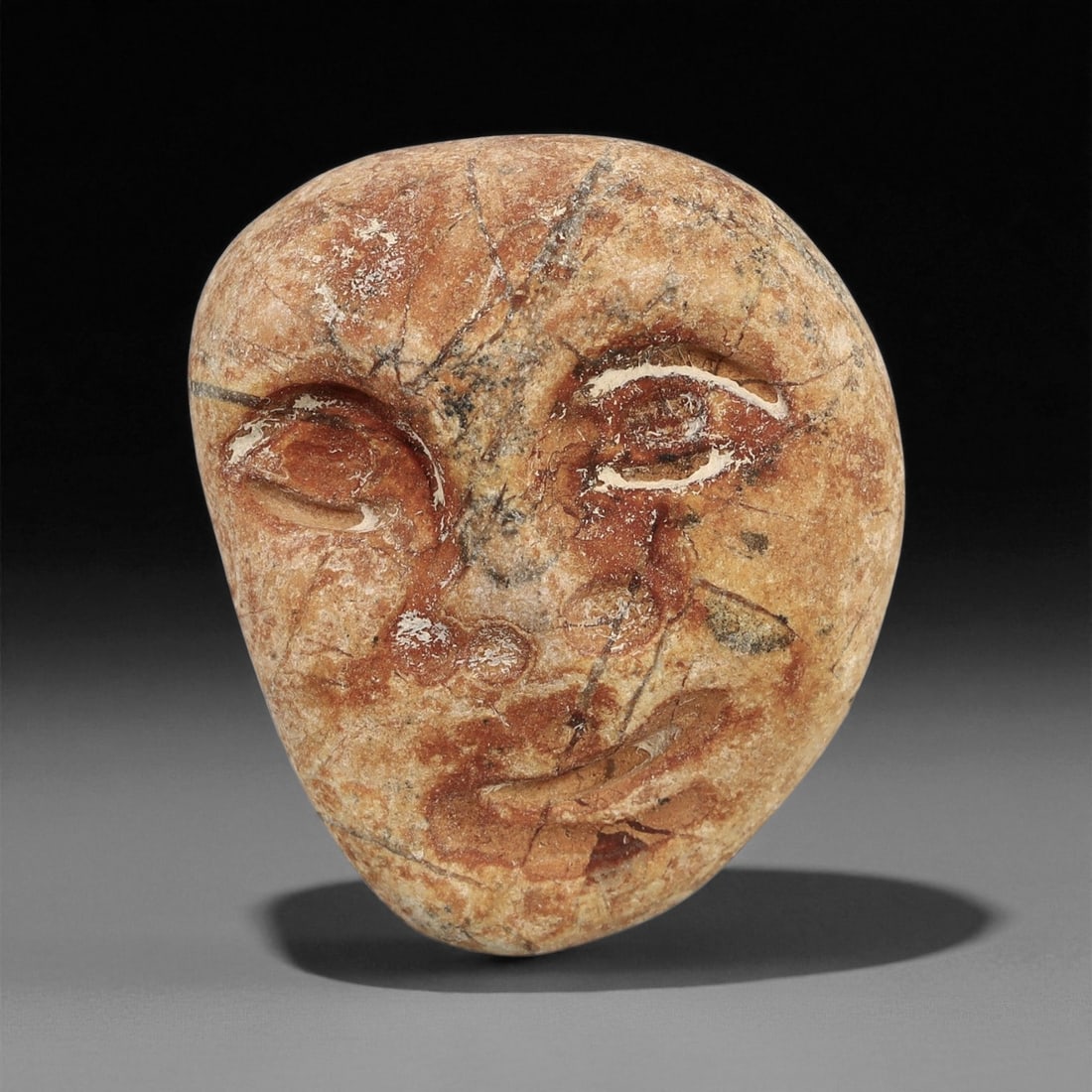 Ancient Medieval Coptic Egyptian Stone Maskette Amulet, c. 6th-9th Century CE, 2.7cm: This delicate and introspective stone maskette, measuring 2.7cm in height, originates from the Coptic Egyptian tradition of the 6th-9th centuries CE. Carved from mottled reddish-beige stone with trace