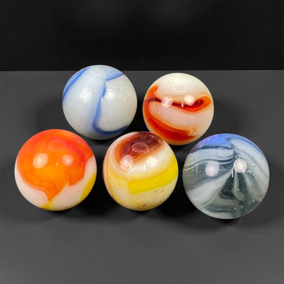 Vintage Glass Marbles Lot, Mid-20th Century, 1.4-1.6cm: This charming lot of vintage glass marbles, dating from the mid-20th century, reflects the artistry and playfulness of early handmade and molded glass craftsmanship. These marbles were produced during