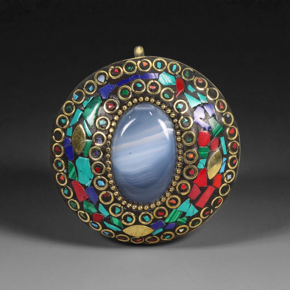 Vintage Himalayan Tribal Mosaic Agate Brass Pendant, 20th Century, 5.5cm: This striking round pendant captures the vibrant artistry of 20th-century Himalayan tribal jewelry, blending spiritual symbolism with masterful craftsmanship. At its center rests a polished blue bande