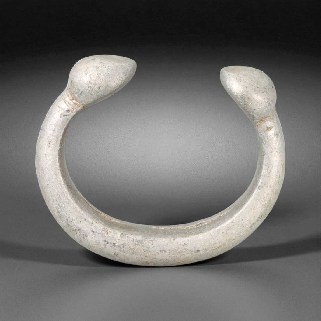 Antique West African Smooth Cast Aluminium Manilla Bracelet, c. Early 20th Century CE, 43g: This rare aluminium manilla bracelet, crafted in the early 20th century CE, represents a transitional phase in West African trade and metallurgy as traditional forms adapted to new materials. Measurin