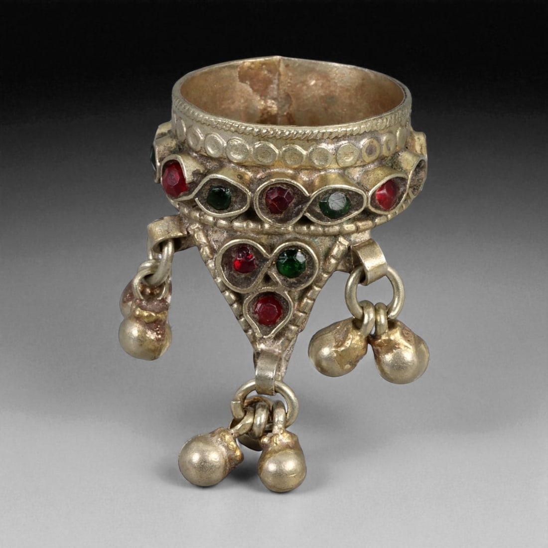 Antique Central Asian Silver Ring with Red and Green Glass Insets Charms, c. 19th-20th Century, 11g: This unusual and highly decorative antique silver ring reflects the playful and symbolic artistry of Central Asian jewelry. The triangular bezel is adorned with alternating red and green glass insets,
