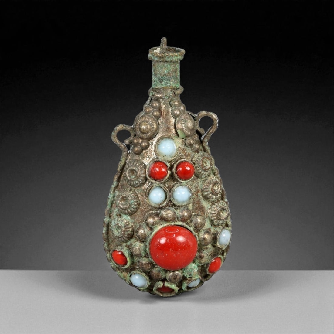 Antique Himalayan Ritual Snuff Flask Pendant with Coral and Glass Inlay, 20th Century, 23g: This ornate tear-shaped pendant, crafted in the 20th century in the Himalayan region-likely Nepal or Tibet-represents a blend of personal ornamentation and ritual utility. Designed in the form of a mi