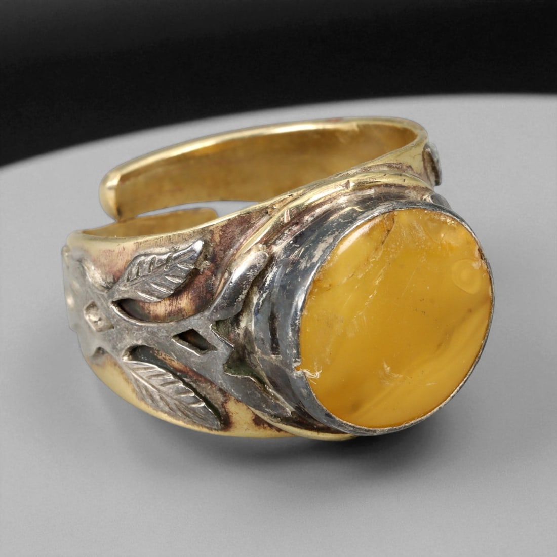 Vintage Himalayan Amber Cabochon Silver Gilt Ring, 20th Century: This bold Himalayan ring, crafted in the 20th century, is centered with a warm amber cabochon, its honey-golden hue glowing with natural inclusions and soft translucence. Set within a silver bezel and