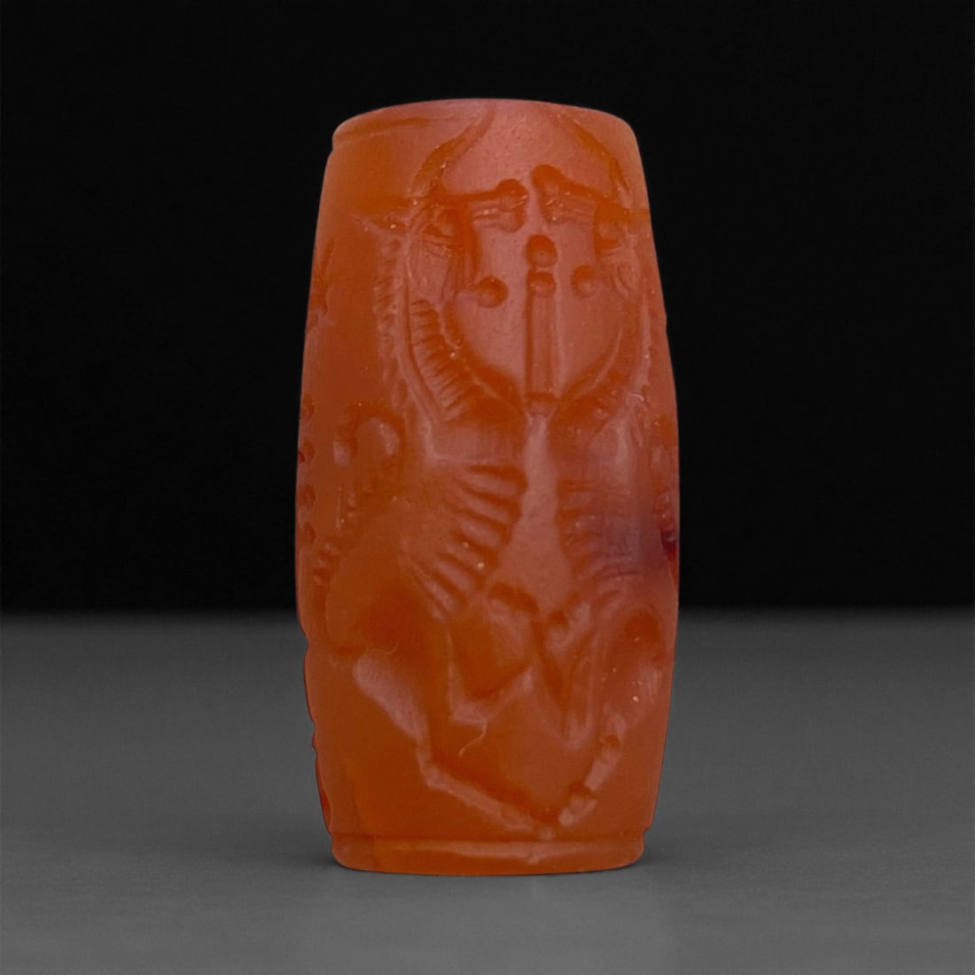 Ancient Akkadian Carnelian Cylinder Seal Depicting Winged Deity, c. 2300-2100 BCE 2.5cm 7g: This remarkable carnelian cylinder seal originates from the Akkadian period of Mesopotamia, circa 2300-2100 BCE - one of the earliest and most artistically accomplished civilizations in recorded histo