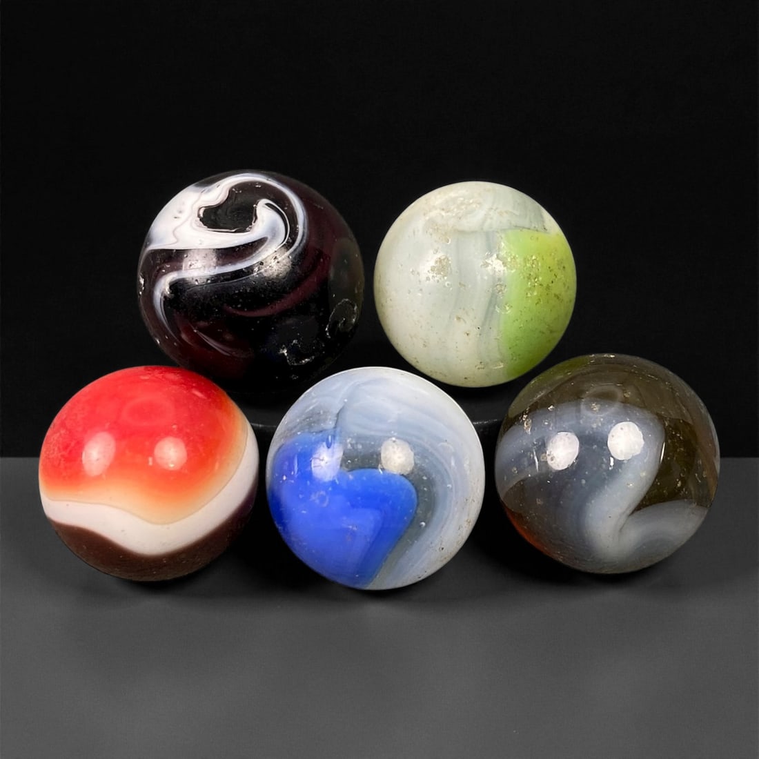 Vintage Glass Marbles Lot, Mid-20th Century, 1.5-1.7cm: This charming lot of vintage glass marbles, dating from the mid-20th century, reflects the artistry and playfulness of early handmade and molded glass craftsmanship. These marbles were produced during