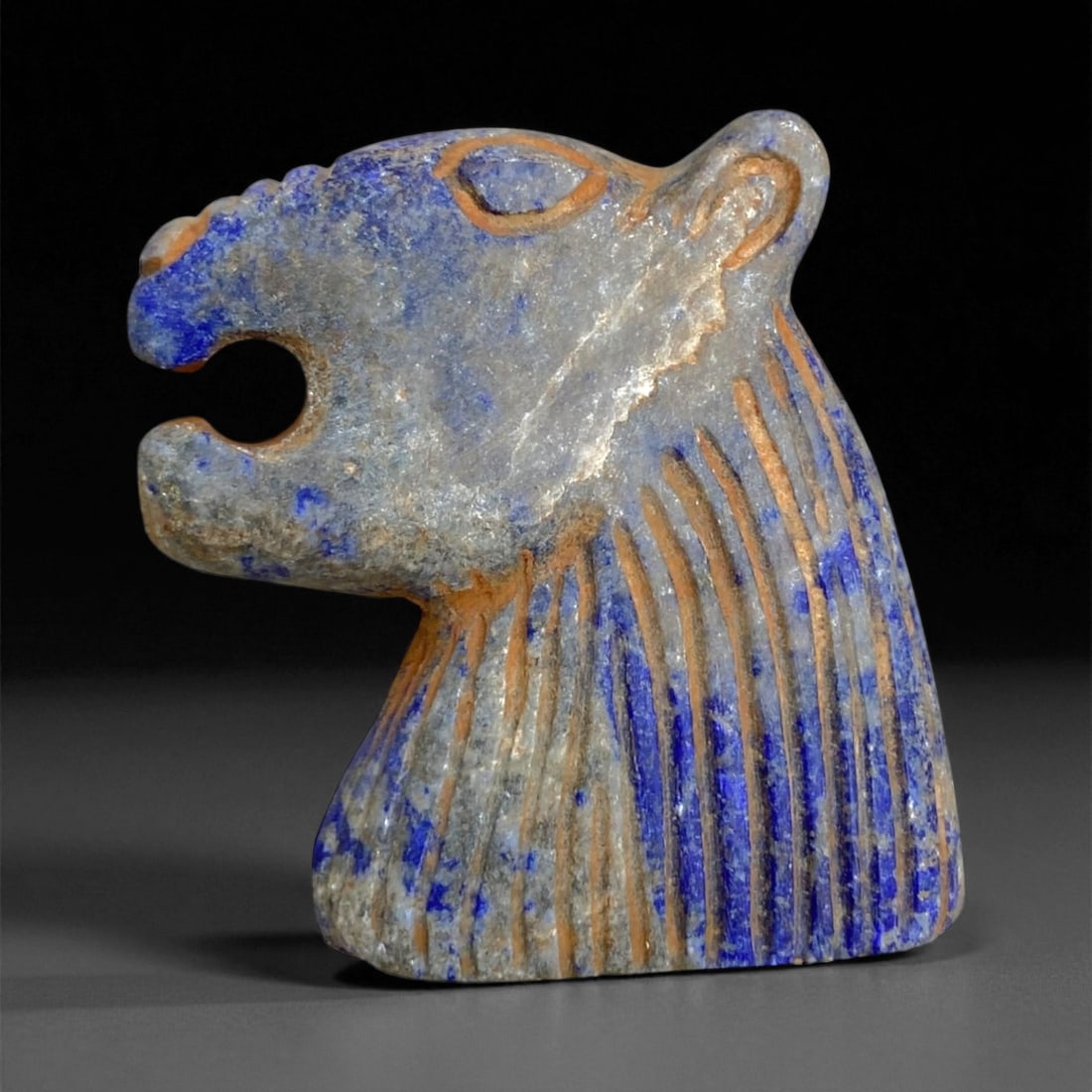 Ancient Bactrian Lapis Lazuli Lion-Head Plaque, c. 2nd-1st Millennium BCE, 3.5cm, 31g: This magnificent lapis lazuli plaque, carved in the form of a roaring lion's head, originates from ancient Bactria, circa 2nd-1st millennium BCE. Bold yet refined, the plaque exemplifies the distincti