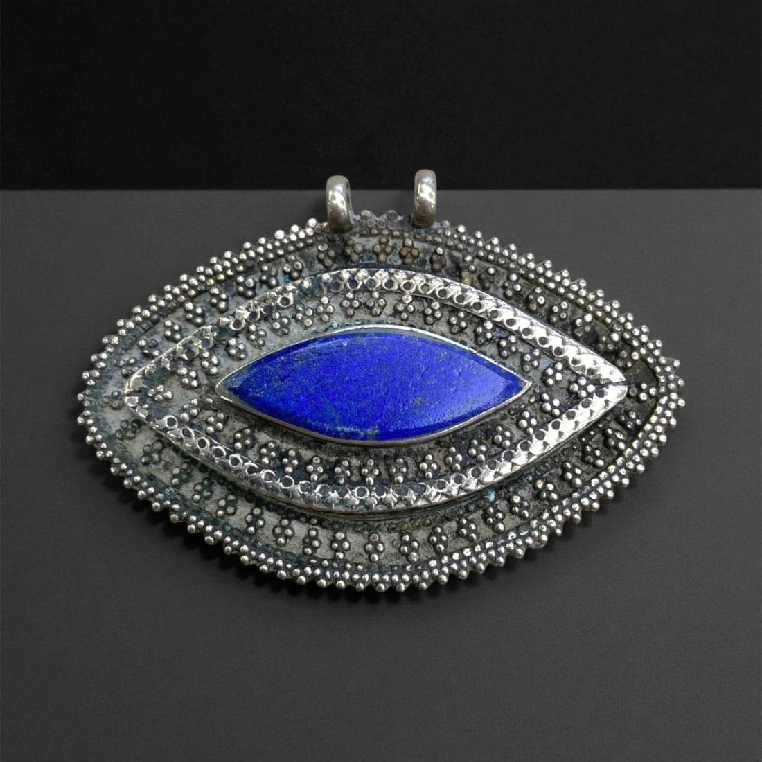 Vintage Central Asian Silver Pendant with Lapis Lazuli Inlay, Mid-20th Century, 7cm, 40g: This elegant vintage pendant, crafted in Central Asia during the mid-20th century, exemplifies traditional metalwork infused with symbolic artistry. Shaped in an almond or "eye" form, the pendant feat