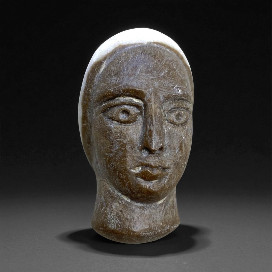 Ancient South Arabian Female Head Amulet in Steatite, c. 1st Millennium BCE, 3cm, 13g: This finely sculpted head-shaped amulet, carved from dark steatite, originates from ancient South Arabia-likely the Sabaean or Qatabanian cultures of modern-day Yemen. Dating to the 1st millennium BCE