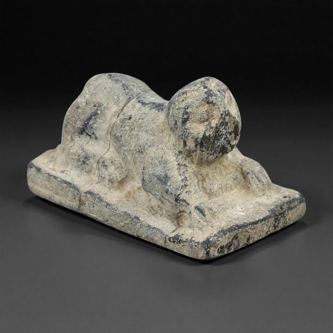 Ancient Akkadian Schist Anthropomorphic Amulet, c. 2300-2100 BCE, 4.8cm: This small yet evocative anthropomorphic amulet, carved from gray schist, dates to the Akkadian period of Mesopotamia (c. 2300-2100 BCE). The figure is shown in a prone or crouching posture upon a fla