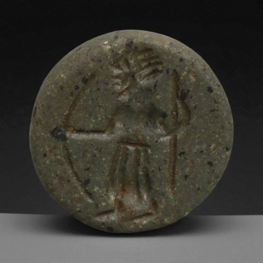 Ancient Neo-Assyrian Hemispherical Green Stone Stamp Seal with Archer, c. 9th-7th Century BCE 13g: This hemispherical stamp seal, carved from green-speckled stone, measures 2.5 cm (1 in) in diameter and weighs 13 g (0.45 oz). The engraving depicts a standing archer, bow drawn, with a spiked crown o