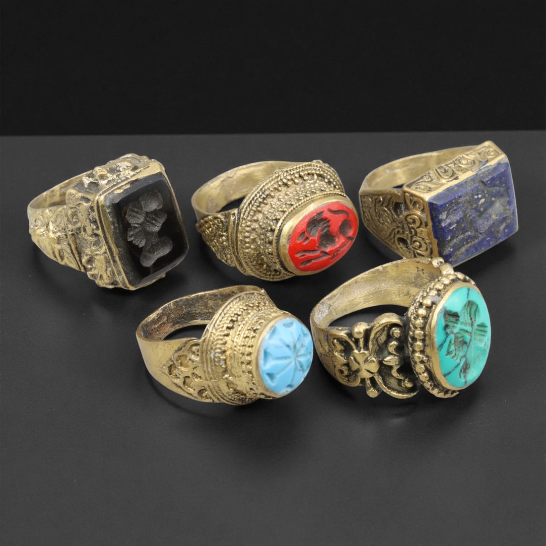 Antique Qajar Royal Gemstone Gilt Brass Rings Set, c. 18th-19th Century,: This refined set of five antique gilt brass rings originates from the Qajar Dynasty of Persia, dating to the 18th-19th century. Each ring is crafted with exquisite ornamental detailing and inset with