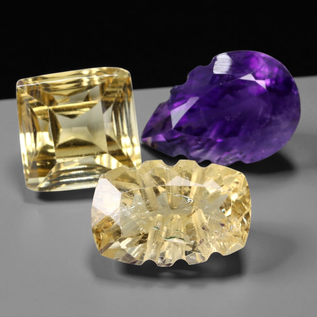 26.33 Carats Citrine and Amethyst Faceted Gemstone Trio - Natural 3-Piece Lot, 1.5 to 1.6 cm: This vibrant trio features two warm golden citrines and one richly saturated amethyst, all precision-cut to showcase quartz's brilliance and versatility. The group includes a radiant square-cut citrin