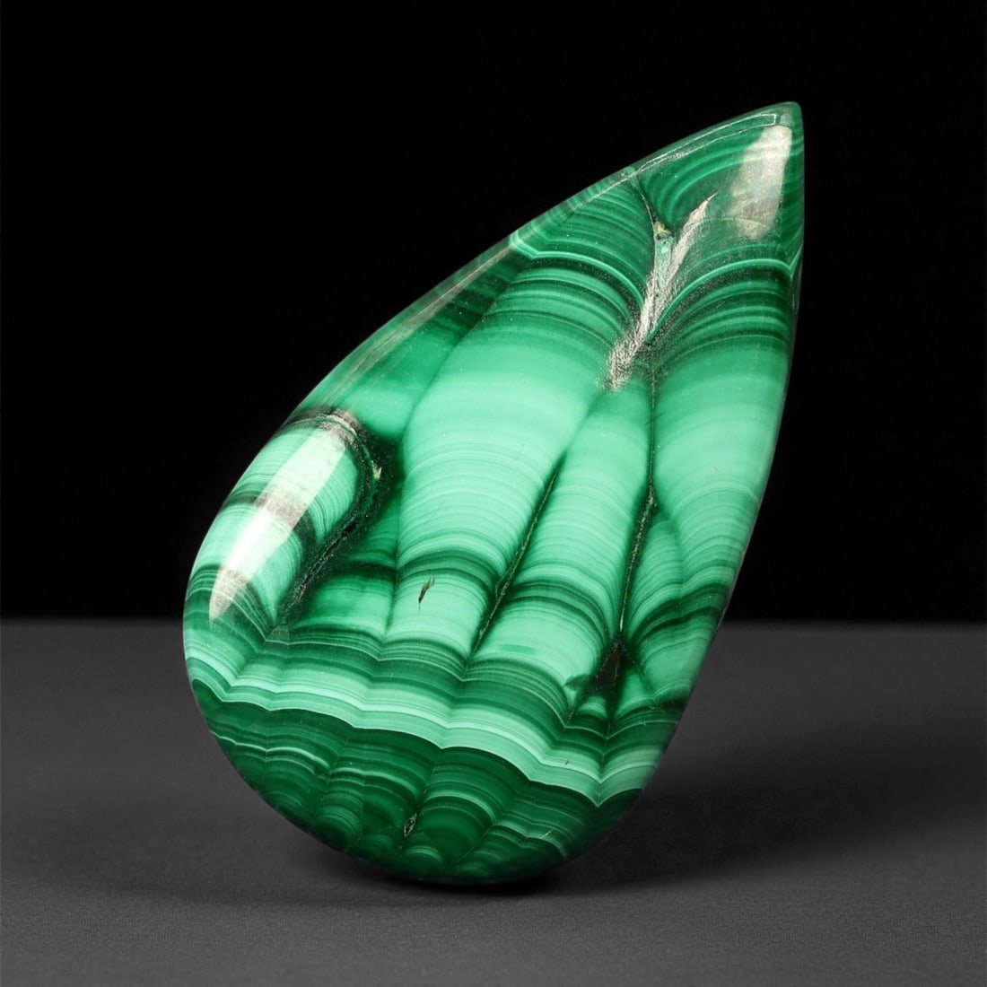 54.85 Carats Striped Green Malachite Cabochon - Natural Teardrop Cut, 3.9 x 2.2 cm: This richly patterned malachite cabochon dazzles with vibrant green banding in concentric waves and flowing stripes, characteristic of high-grade material. The teardrop shape is expertly polished, all