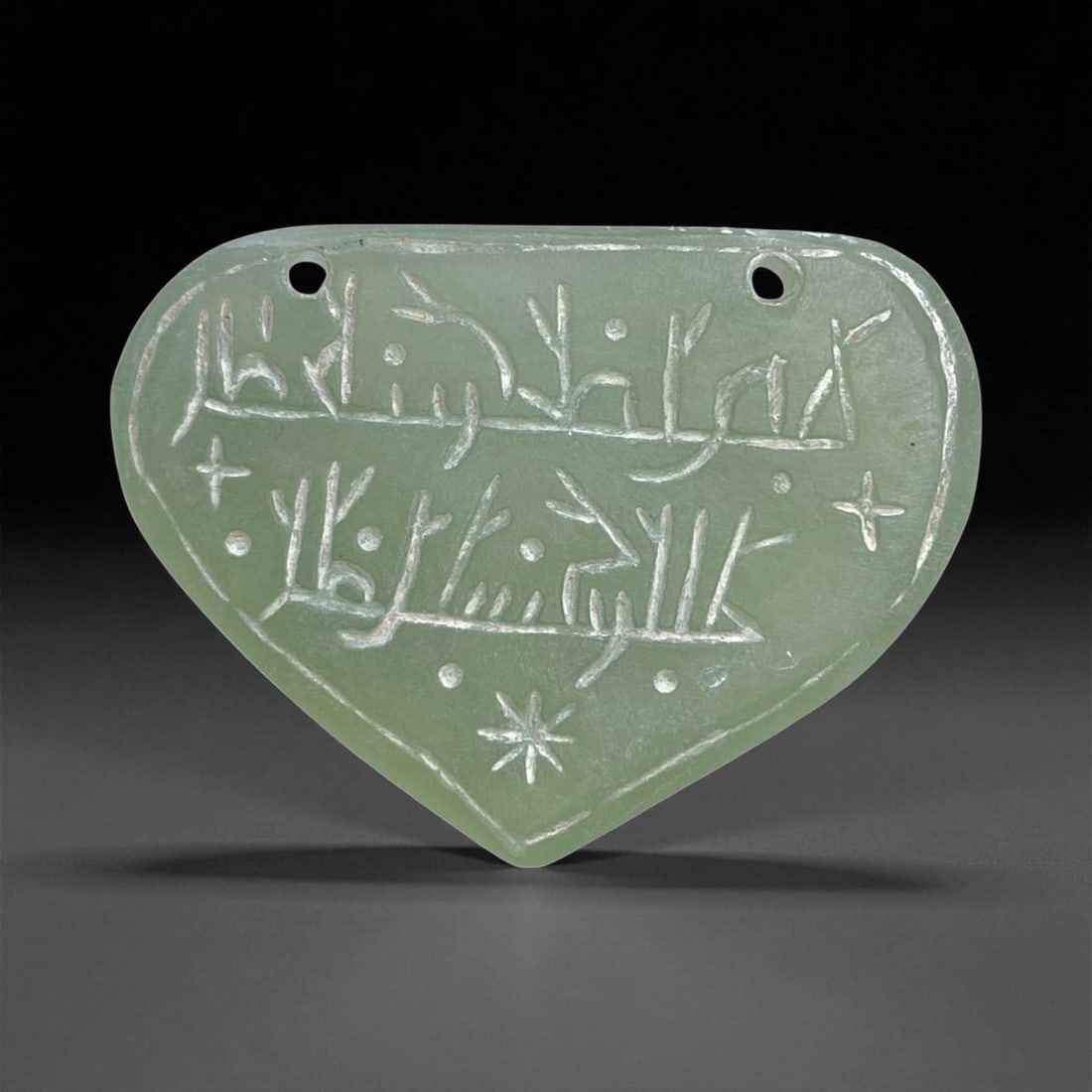 A Islamic Jade Amulet with Inscription, Medieval Period (c. 12th-14th Century CE), 18g, 5cm, 50AA: This elegantly carved jade amulet, dating to the Islamic Medieval Period (likely 12th-14th century CE), embodies the synthesis of artistry and spirituality that defined Islamic lapidary work during th