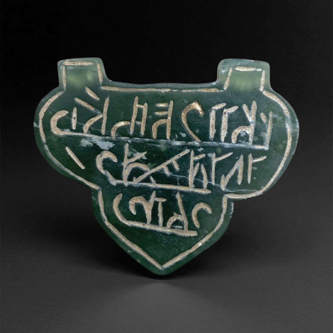 A Islamic Jade Amulet with Inscription, Medieval Period (c. 12th-14th Century CE), 13g, 4cm, 48AA: This elegantly carved jade amulet, dating to the Islamic Medieval Period (likely 12th-14th century CE), embodies the synthesis of artistry and spirituality that defined Islamic lapidary work during th