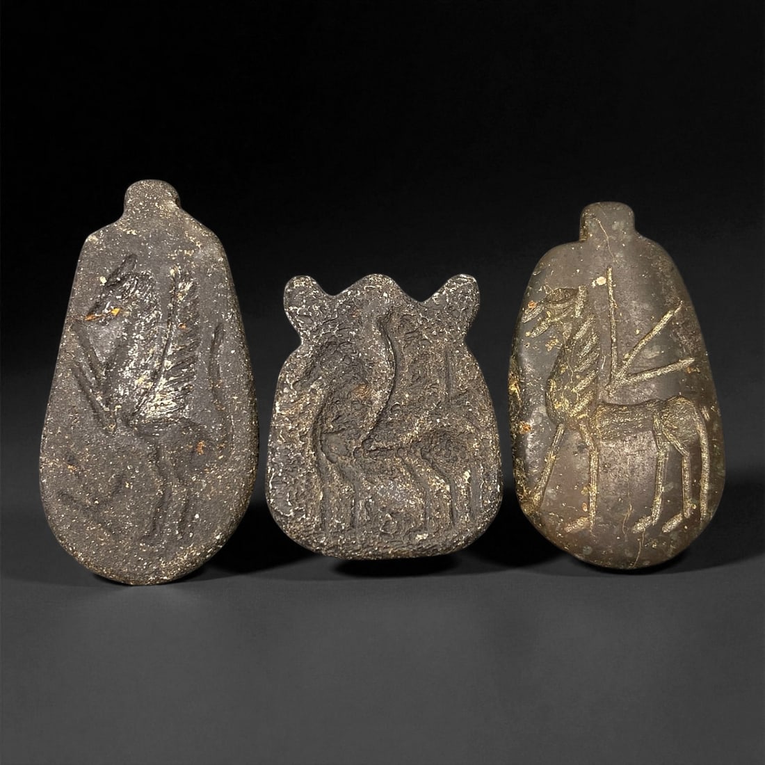 Ancient Neo-Assyrian Steatite Amulet Group, c. 8th-7th Century BCE, 3.3-4.7cm, 28EK: This rare assemblage of three carved steatite amulets originates from the Neo-Assyrian period, a pinnacle of Mesopotamian artistry renowned for its intricate symbolism and protective talismans. Each p