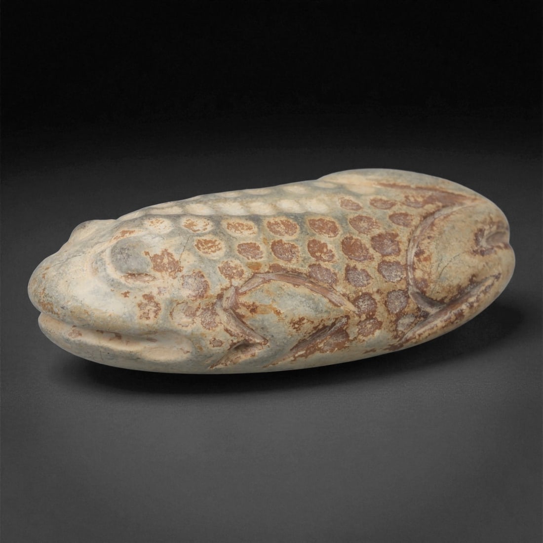 A Near Eastern Stone Amphibian Figure, 3rd-2nd Millennium BCE, 43LB: Carved from a pale stone with brown surface accretions, the object depicts an elongated amphibian with a rounded head, a gently tapering body, and a flattened underside. The eyes are indicated by rais