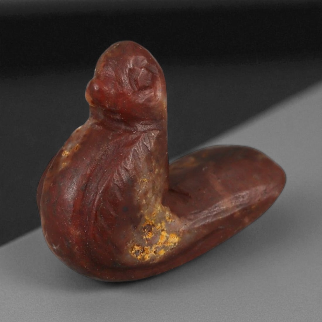 Ancient Egyptian Agate Bird Amulet, c. 1st Millennium BCE 1.8g, 82B: This delicately carved amulet, measuring 1.7 cm and weighing 1.8 grams, is fashioned from deep red-brown agate and depicts a stylized bird, likely a duck or dove. The smooth form, combined with incise