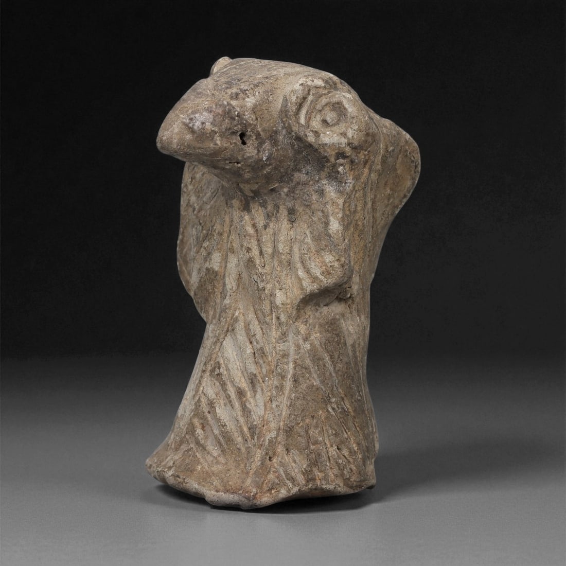 A Near Eastern Terracotta Anthropomorphic Bust, 2nd-1st Millennium BCE, 39LD: Modeled from light brown terracotta with surface accretions, the bust depicts a stylized anthropomorphic figure with a prominent, elongated head and large circular eyes formed by concentric grooves. T