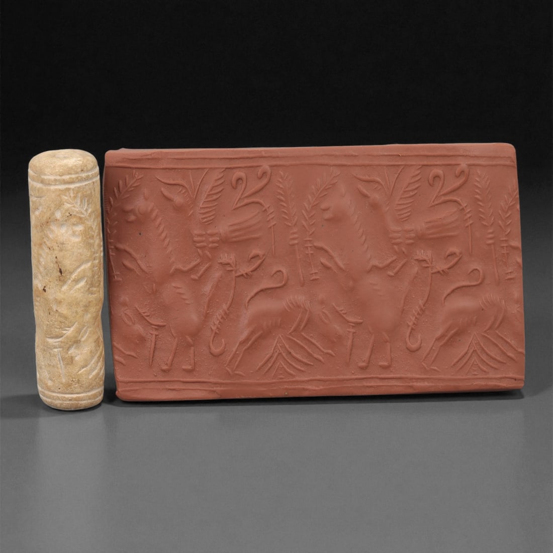 A Near Eastern Stone Cylinder Seal, 2nd-1st Millennium BCE, 13LE: Carved from a light beige stone with surface mottling, the cylindrical seal is engraved in shallow intaglio with a continuous frieze of upright and recumbent quadrupeds arranged among stylised trees o