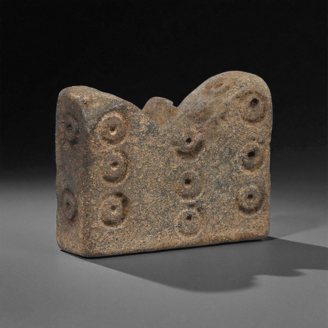 A Near Eastern Stone Decorated Block, 3rd-2nd Millennium BCE, 86LF: Carved from a coarse-grained brown stone with mottled surface accretions, the object is a rectangular block with a gently undulating upper contour. Both principal faces bear a grid-like arrangement of