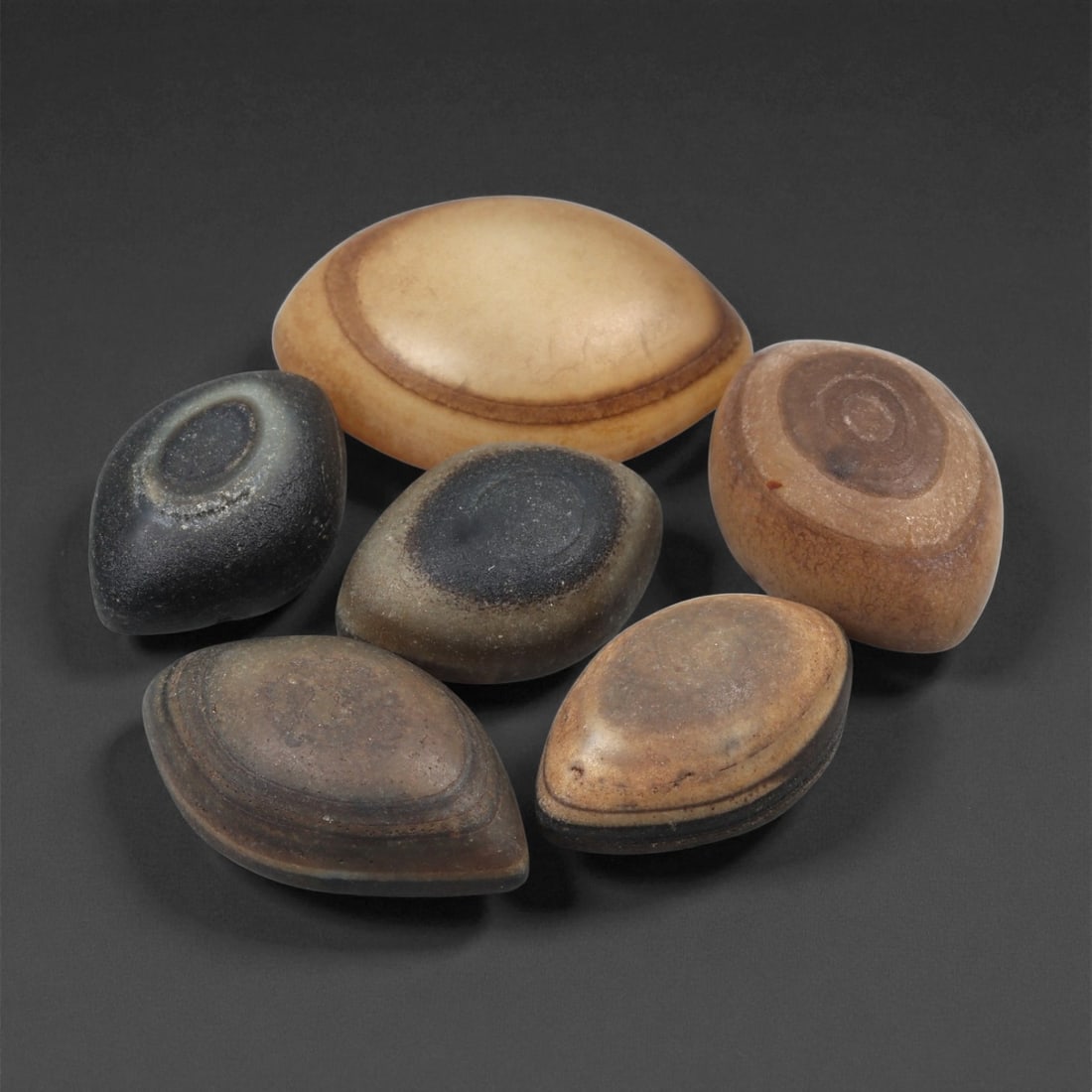 A Group of Tibetan Stone Luk Mik ("Goat Eye") Beads, 19th-Early 20th Century, 25LG: Carved from banded agate and chalcedony, the group comprises six domed, oval, and lenticular beads characterized by concentric circular banding that creates the "eye" motif associated with luk mik for