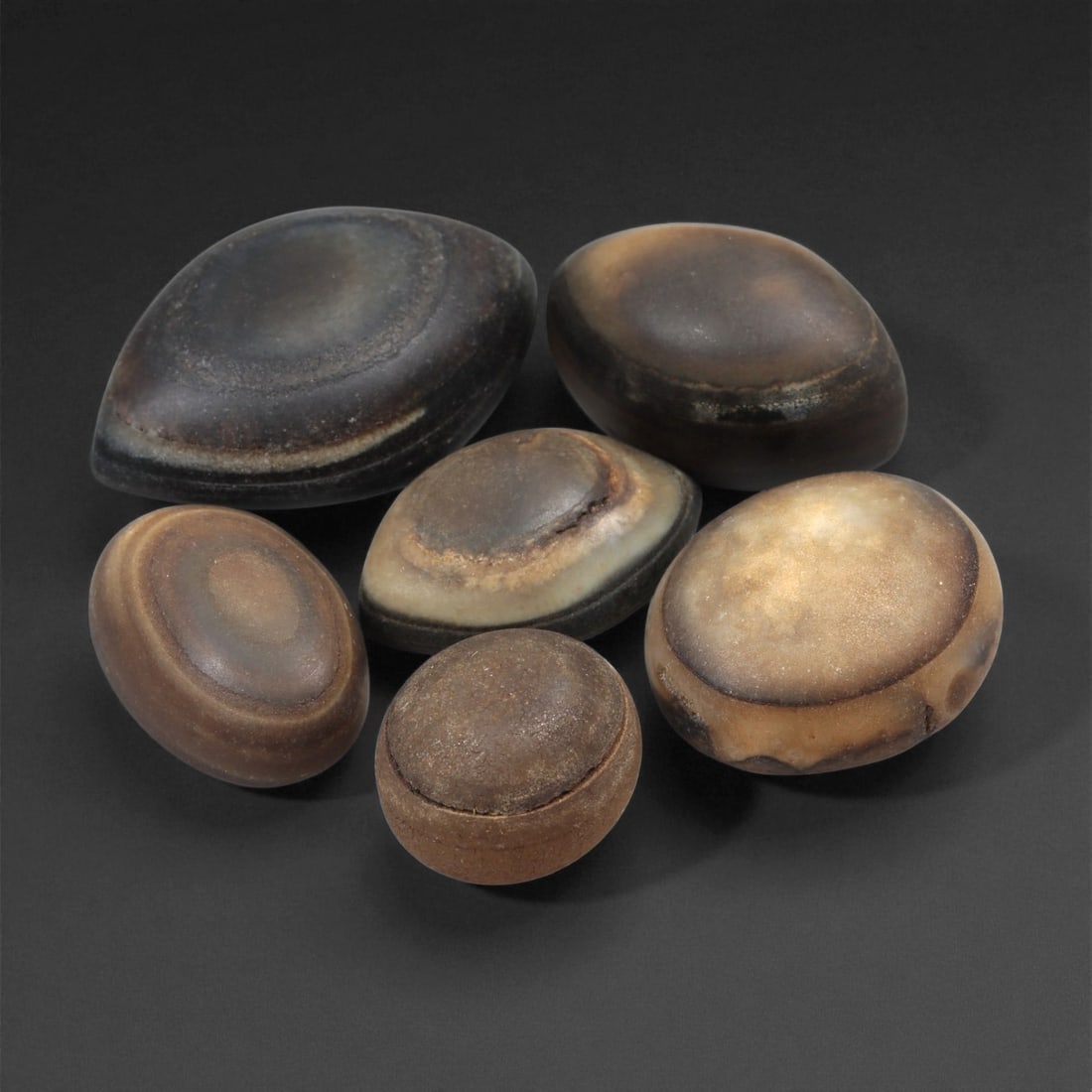 A Group of Tibetan Stone Luk Mik ("Goat Eye") Beads, 19th-Early 20th Century, 23LG: Carved from banded agate and chalcedony, the group comprises six domed, oval, and lenticular beads characterized by concentric circular banding that creates the "eye" motif associated with luk mik for