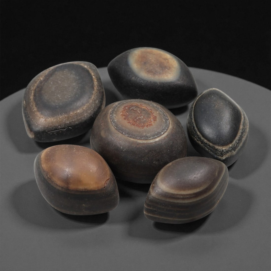 A Group of Tibetan Stone Luk Mik ("Goat Eye") Beads, 19th-Early 20th Century, 29LG: Carved from banded agate and chalcedony, the group comprises six domed, oval, and lenticular beads characterized by concentric circular banding that creates the "eye" motif associated with luk mik for