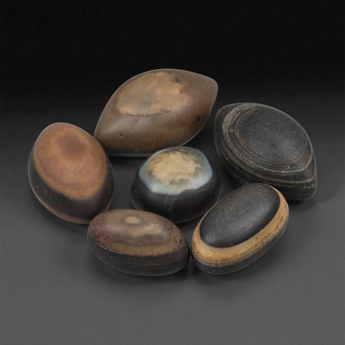 A Group of Tibetan Stone Luk Mik ("Goat Eye") Beads, 19th-Early 20th Century, 21LG: Carved from banded agate and chalcedony, the group comprises six domed, oval, and lenticular beads characterized by concentric circular banding that creates the "eye" motif associated with luk mik for