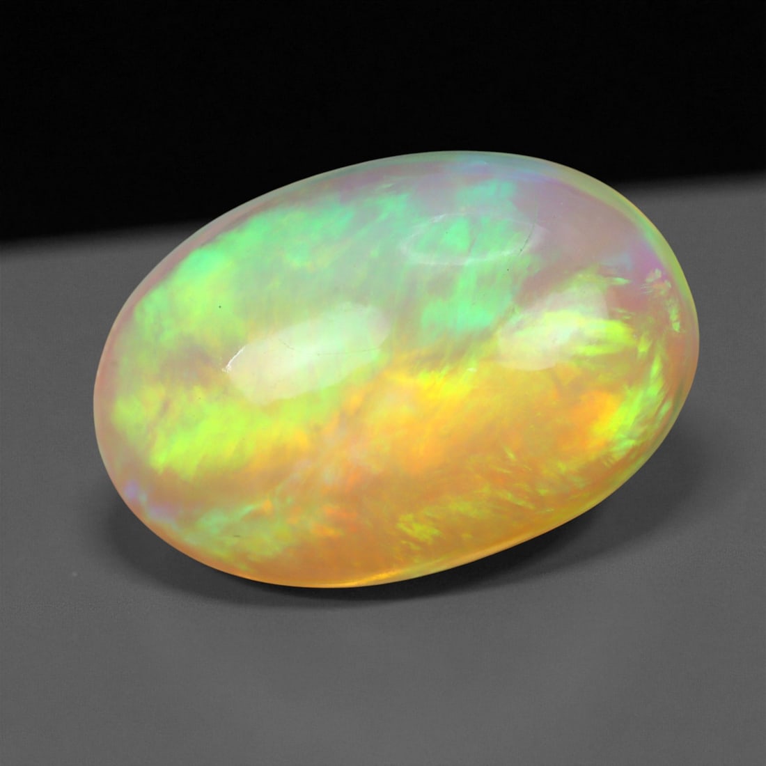3.32 Carats Pastel Neon Welo Opal Cabochon - Natural Ethiopian Gemstone, 29XE: This glowing Welo opal shimmers with delicate flashes of mint green, lavender, sky blue, and soft amber beneath a translucent, honey-toned body. Its internal light play is gentle yet vivid, with broad