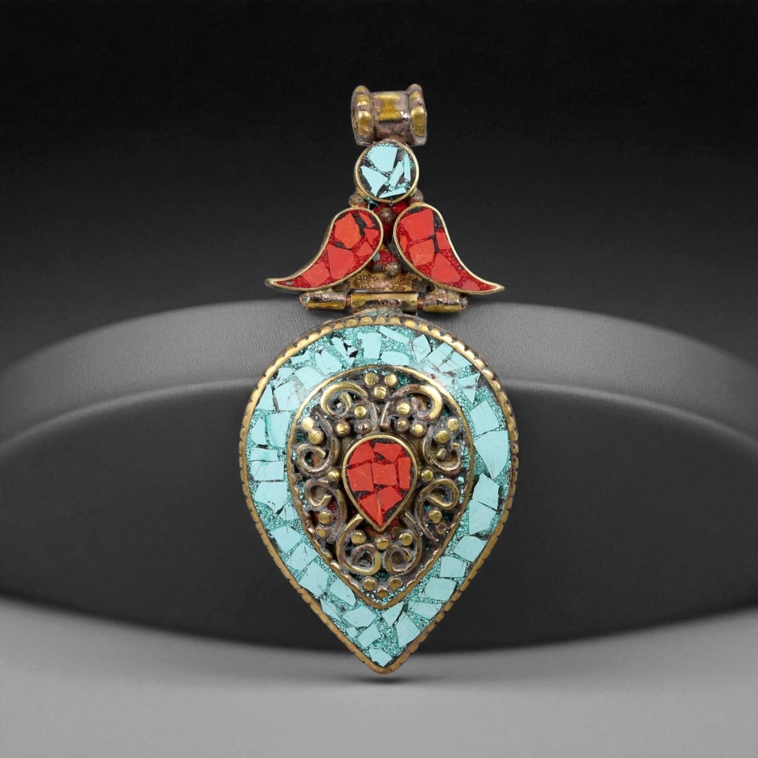 Vintage Himalayan Gilt Copper Turquoise Coral Heart Form Pendant, 20th Century, 8cm, 55CF: This vibrant Himalayan pendant, crafted in the 20th century, takes the form of a stylized heart, richly adorned with turquoise and coral mosaic. The central teardrop-shaped coral is framed by swirling