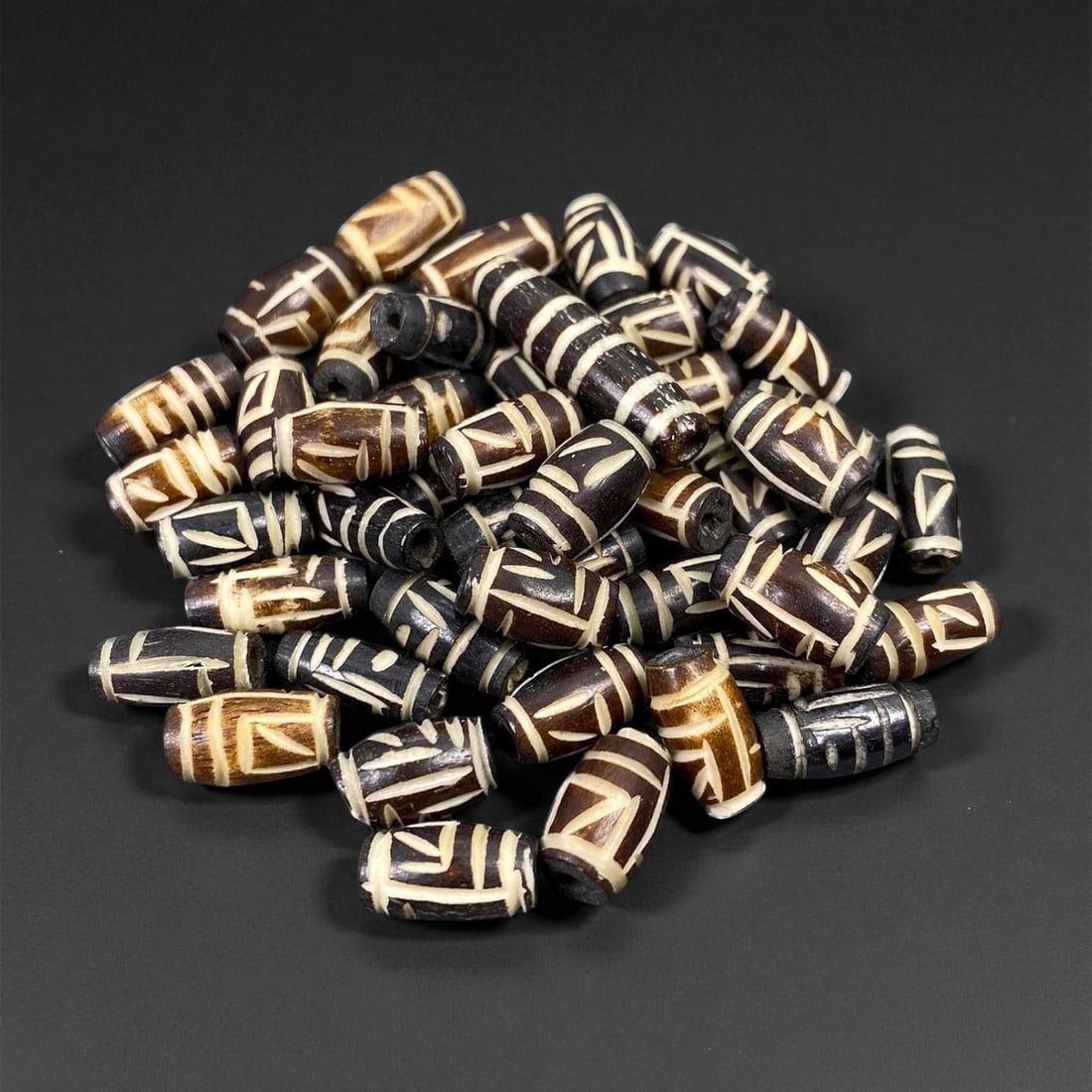 Mid-20th Century Tibetan Hand-Carved Wood Beads, 1.1-2.5cm, 21EP: A collection of Tibetan wood beads, each individually carved and polished, showcasing the natural beauty of the dark-stained grain with contrasting pale surface decoration. These mid-century examples 