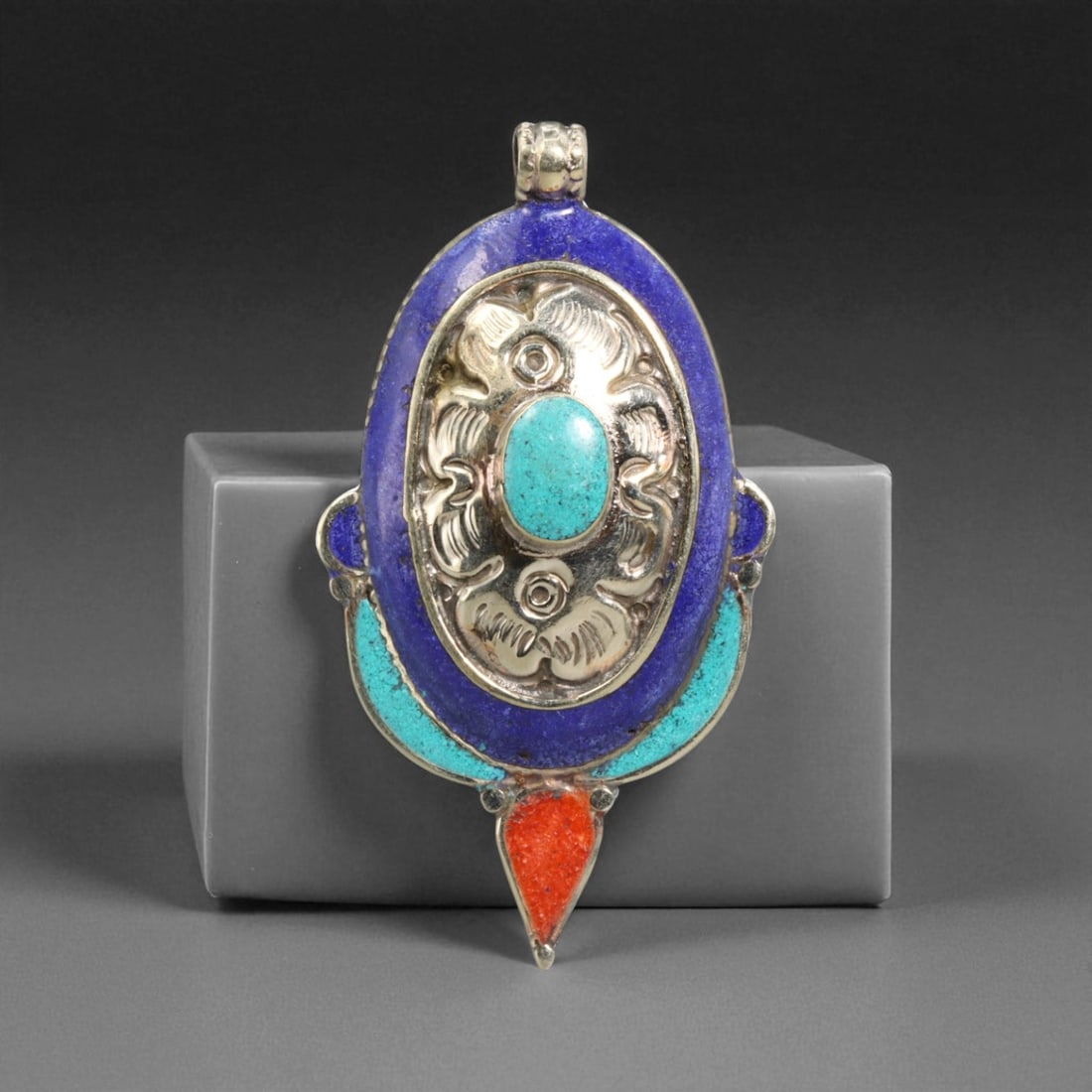 Tibetan Oval Turquoise Lapis Coral Silver Pendant, Sacred Flame Motif, 36.5g, 71W: This striking Tibetan pendant merges elemental symbolism with elegant design, centered around an oval turquoise cabochon embraced by raised silver repousse. Surrounded by rich lapis and turquoise inla