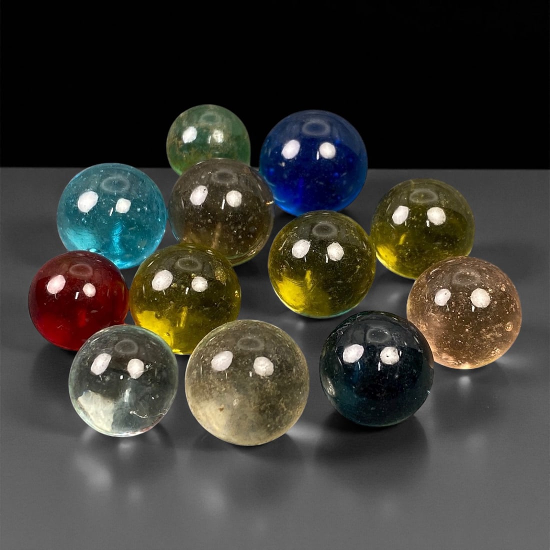 Vintage Glass Marbles Lot, Mid-20th Century, 1.2-1.5cm, 95EK: This charming lot of vintage glass marbles, dating from the mid-20th century, reflects the artistry and playfulness of early handmade and molded glass craftsmanship. These marbles were produced during