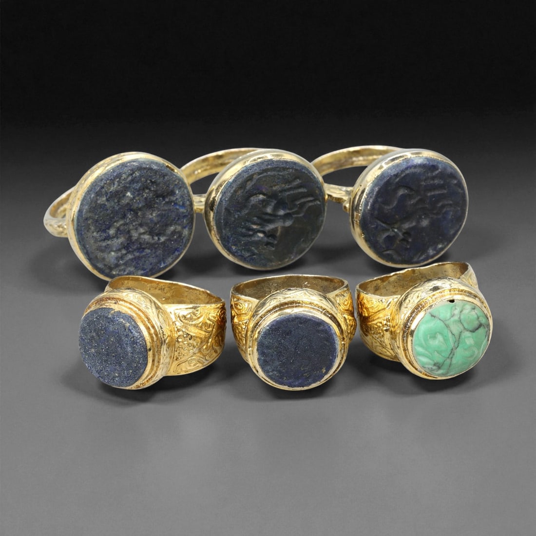 Antique Qajar Gilt Brass Lapis and Turquoise Rings Set, c. 19th Century US 7.75-9, 14ES: This set of six antique Qajar gilt brass rings, sized US 7.75-9, reflects the refined decorative sensibilities of 19th century Persia. Each ring features a broad bezel framed in warm, gold-toned gildi