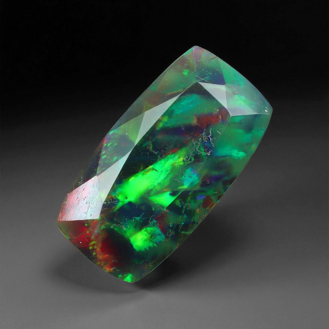 3.22 Carats Electric Green Faceted Black Opal - Natural Ethiopian Gemstone, 17XE: This striking black opal captivates with an electric green blaze streaked with crimson and flashes of neon blue, dramatically showcased through precision faceting. The elongated fancy cut enhances the