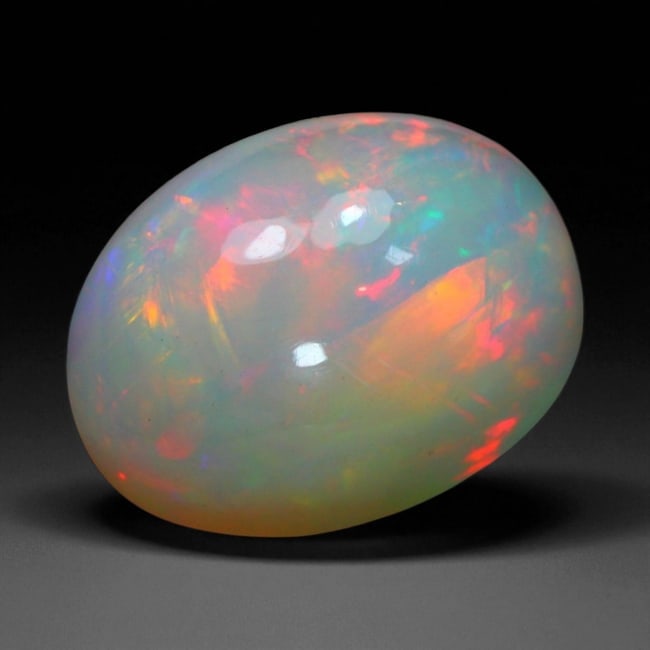 7.42 Carats Fiery Play-of-Color Welo Opal Oval Cabochon - Natural Ethiopian Stone, 37WE: This mesmerizing Welo opal radiates a luminous play-of-color that dances across its translucent body in vivid flashes of red, orange, green, and violet 14.9x11.1x9.2mm. The gem's opalescent base glows