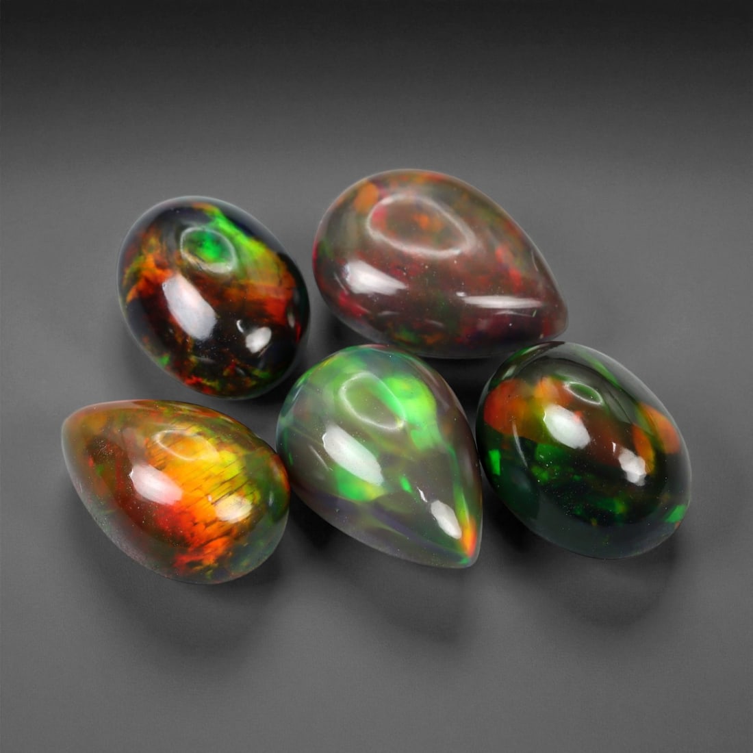 10.30 Carats Fiery Black Opal Selection - Natural Ethiopian Cabochons - 10 to 11 mm, 50XE: This dramatic selection of black opals captivates with intense flashes of crimson, emerald, and molten orange, all set against deep, inky body tones that amplify their internal fire. Each stone displa