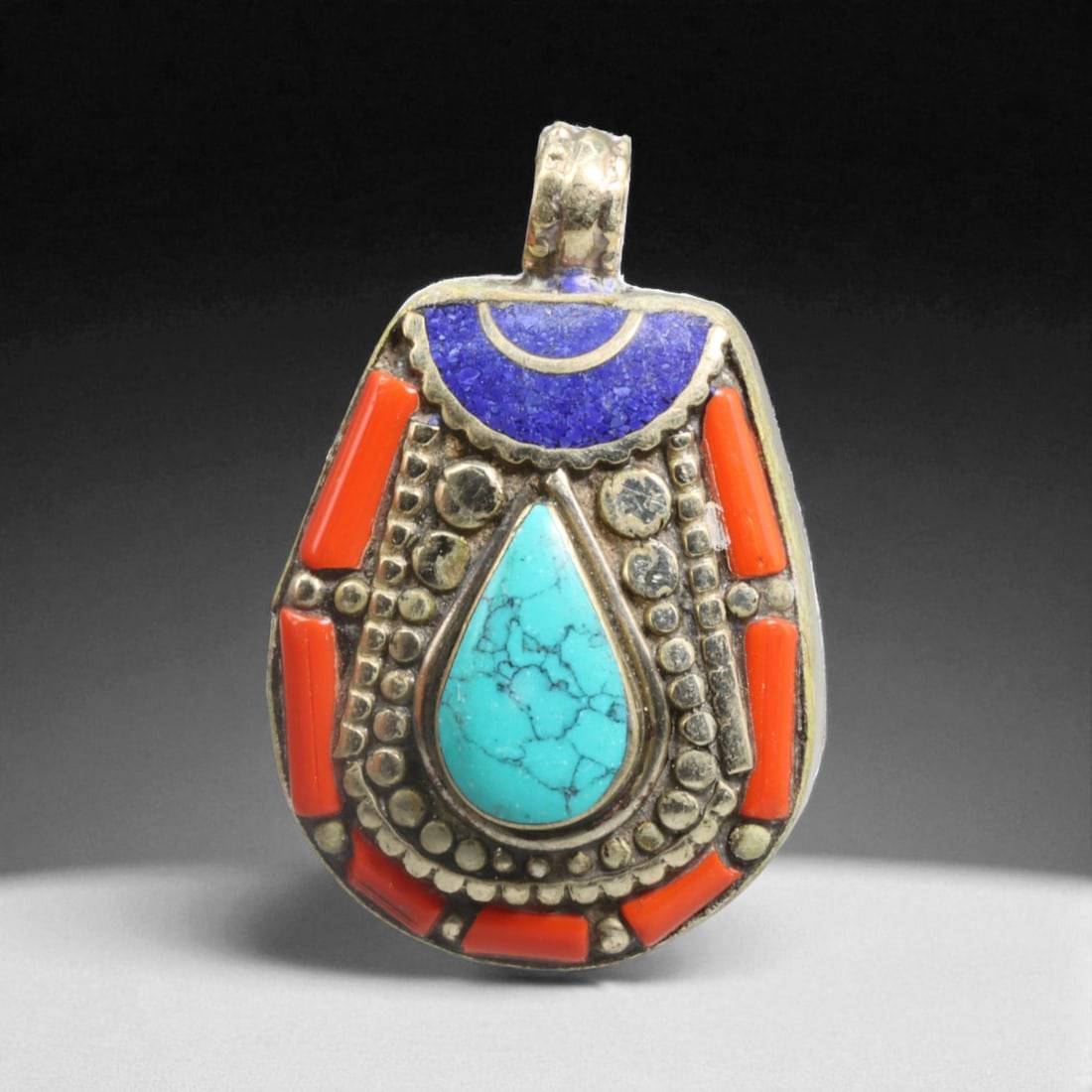 Petite Tibetan Pendant with Teardrop Turquoise, Coral & Lapis Inlay - 27g, 66V: This small yet visually commanding Tibetan pendant is a masterclass in ornamental density and symbolic layering. At its heart lies a teardrop-shaped turquoise stone, delicately veined and deeply satur