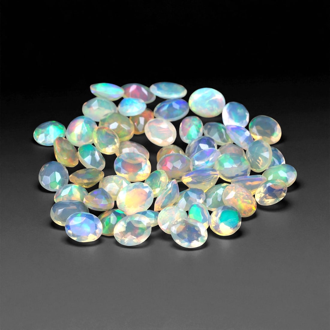 9.75 Carats Oval Cabochon Opal Parcel - Natural Welo Ethiopian Stones, 46XC: This mesmerizing parcel features 4x3 mm oval-cut opals, each glowing with exceptional play-of-color across a luminous, translucent body. Flashes of electric green, oceanic blue, and golden orange shif