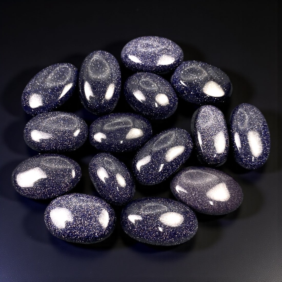 128.32 Carats Midnight Blue Goldstone Cabochon Lot - Freeform Cuts, 14-19 mm, 81XB: This striking parcel features a collection of polished blue goldstone cabochons, each ranging from 14 to 19 mm in size. With their deep navy base and sparkling metallic inclusions, these stones shimme