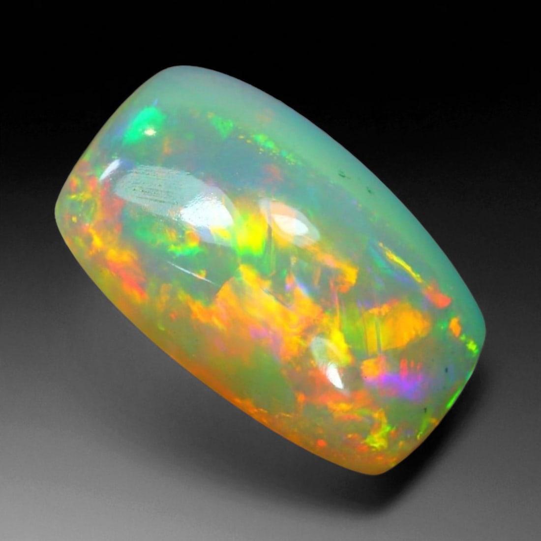 5.54 Carats Fiery Play-of-Color Welo Opal Oval Cabochon - Natural Ethiopian Stone, 77WE: This mesmerizing Welo opal radiates a luminous play-of-color that dances across its translucent body in vivid flashes of red, orange, green, and violet 15.3x9.5x7mm. The gem's opalescent base glows wi