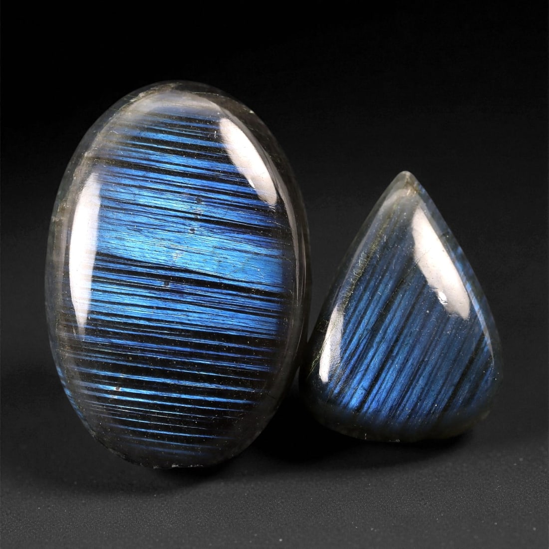59.65 Carats Midnight Blue Labradorite Pair - Natural Madagascar Cabochons, 53XC: This striking duo of labradorite cabochons reveals a dramatic linear display of metallic midnight blue with silken black striations. Each stone radiates a strong labradorescent sheen that shifts with 
