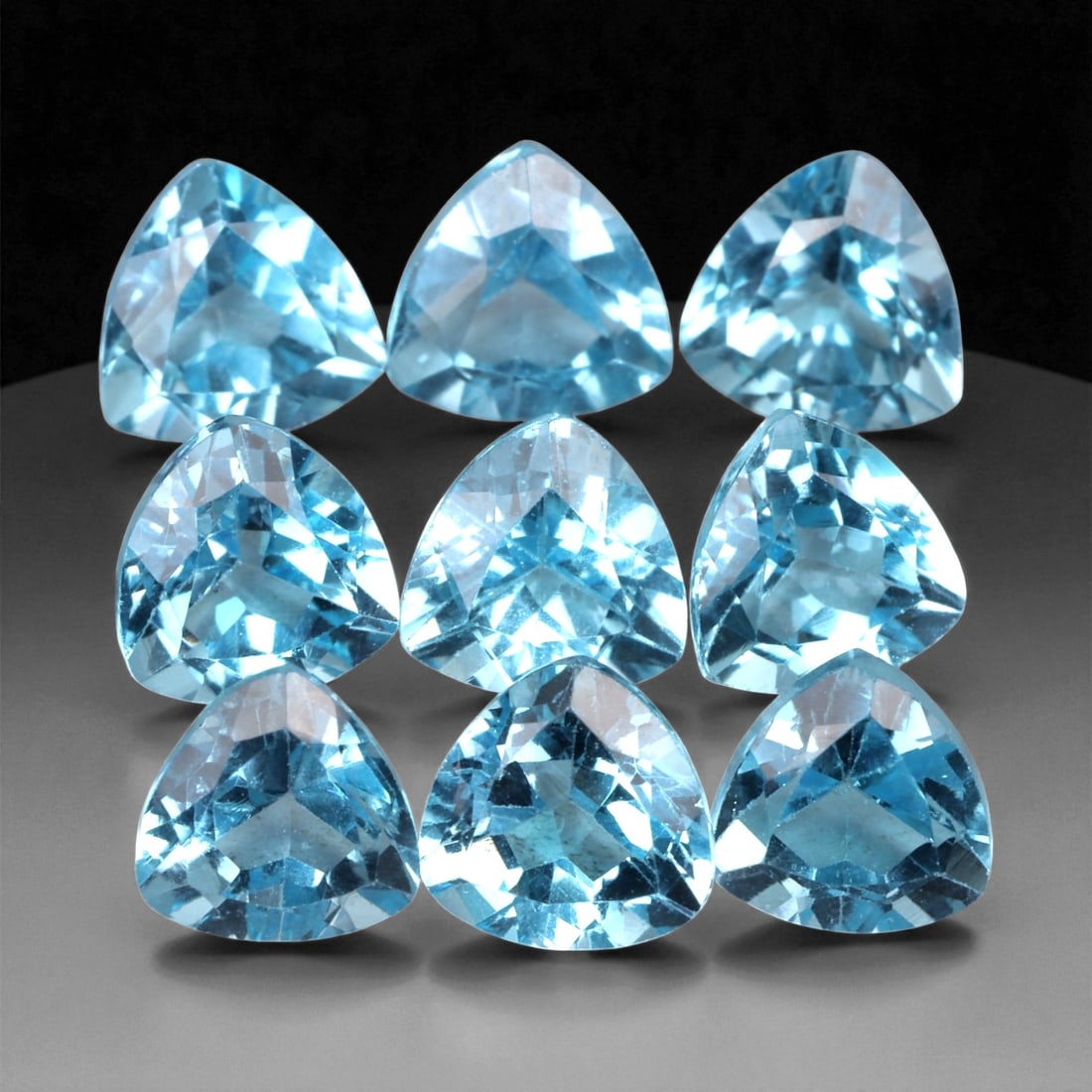 9.83 Carats Sky Blue Topaz Trillion Parcel - Natural Loose Gemstones, 8XB: This vivid parcel of sky blue topaz features nine expertly faceted trillion-cut gems, each measuring 6 mm and radiating with icy brilliance. The stones display a crisp, refreshing blue hue reminiscent