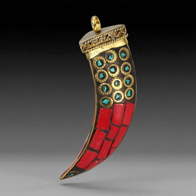 Himalayan Gilt Metal, Coral, and Turquoise-Inset Pendant, 20th Century, 65XD: Fashioned in gilt metal over a dark ground, the pendant is formed as an elongated, curved element with a flat upper rim fitted with a suspension loop. The surface is inlaid with rectangular coral plaq
