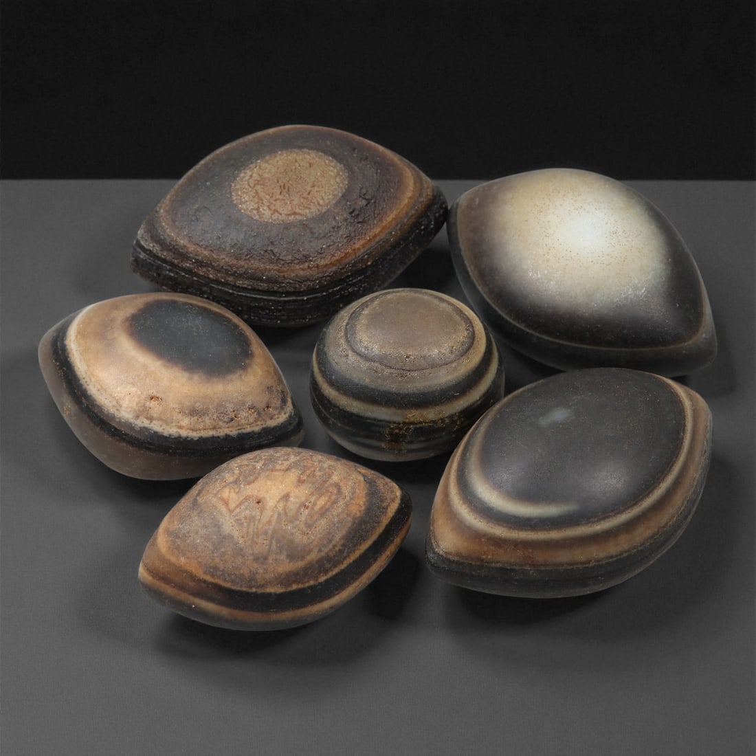 A Group of Tibetan Stone Luk Mik ("Goat Eye") Beads, 19th-Early 20th Century, 17LG: Carved from banded agate and chalcedony, the group comprises six domed, oval, and lenticular beads characterized by concentric circular banding that creates the "eye" motif associated with luk mik for