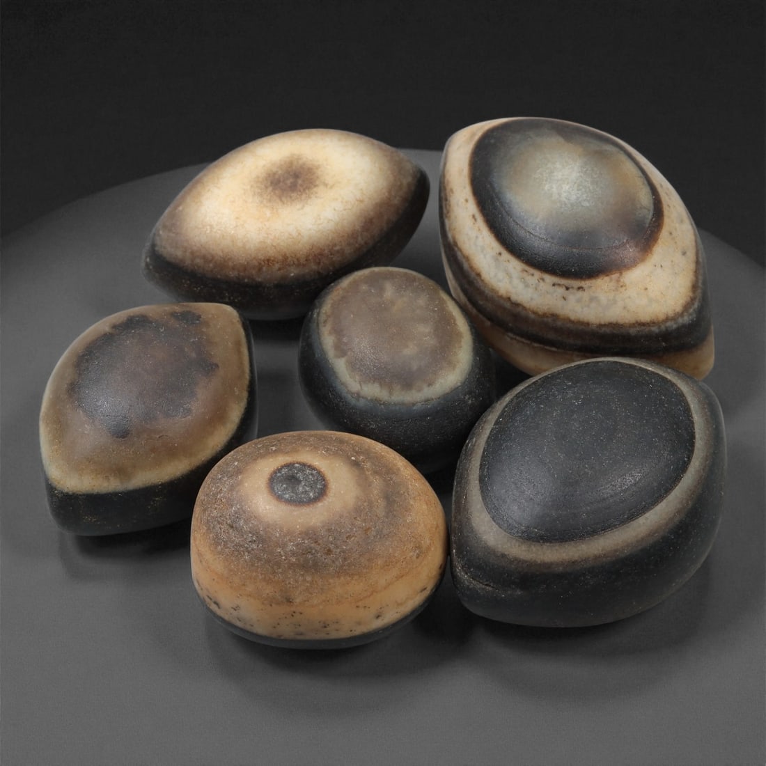 A Group of Tibetan Stone Luk Mik ("Goat Eye") Beads, 19th-Early 20th Century, 14LG: Carved from banded agate and chalcedony, the group comprises six domed, oval, and lenticular beads characterized by concentric circular banding that creates the "eye" motif associated with luk mik for