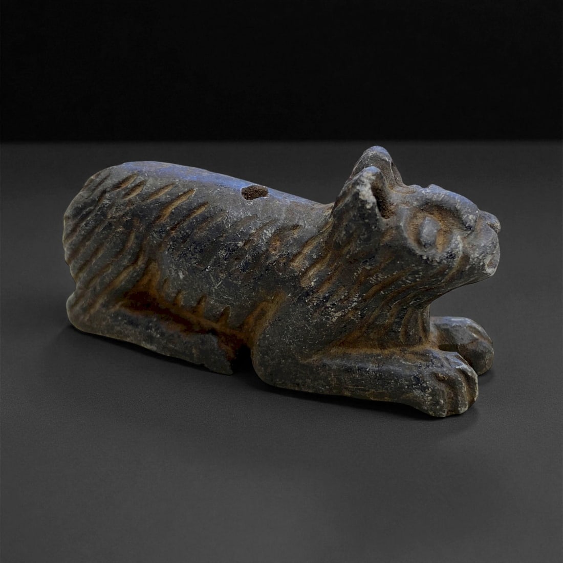 Ancient Elamite Steatite Feline Amulet, c. 2nd Millennium BCE, 6cm, 49g, 75CC: This ancient feline amulet, carved from dark steatite and dating to the Elamite civilization (c. 2nd millennium BCE), is a superb example of early Near Eastern zoomorphic artistry. Depicting a crouchi