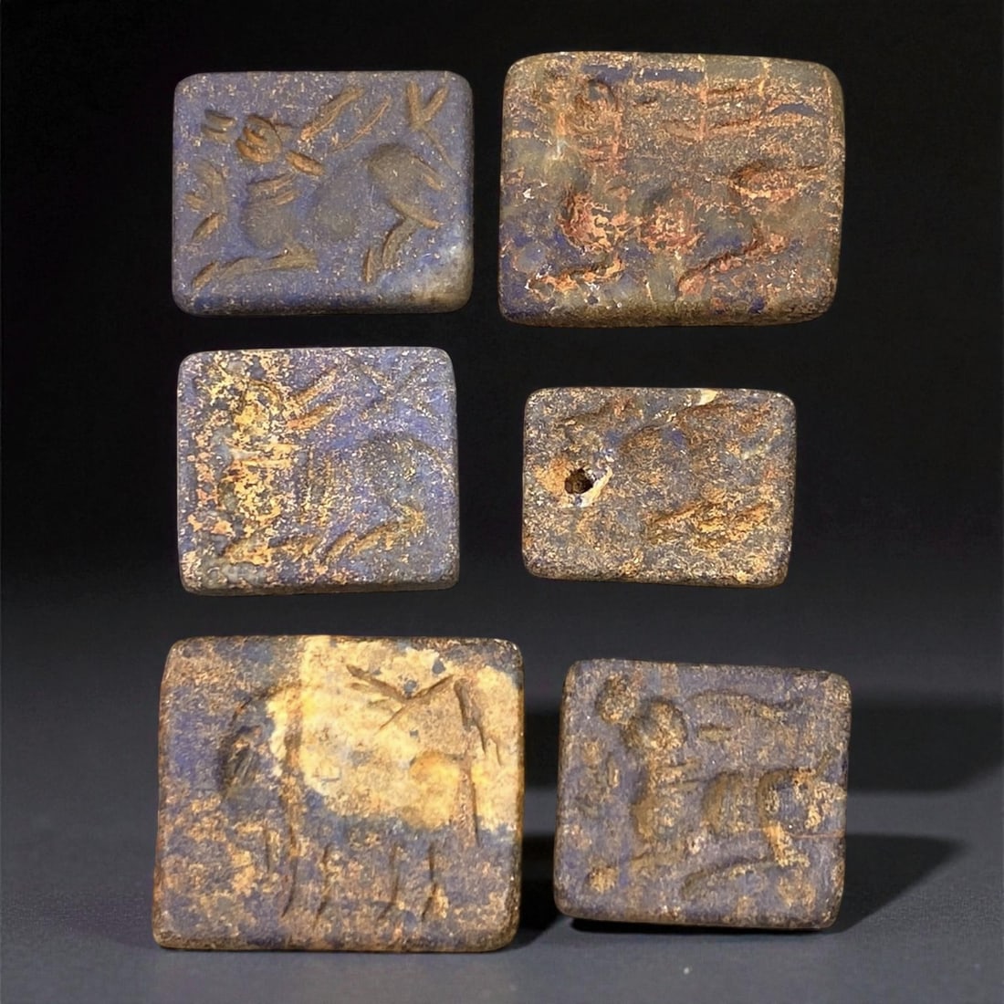 A Akkadian Lapis Lazuli Stamp Seals with Animal Motifs, c. 23rd-21st Century BCE, 1.5-2 cm, 41EK: These six rectangular double-convex stamp seals, carved from deep blue lapis lazuli, date to the Akkadian period of Mesopotamia, around the 23rd to 21st centuries BCE. Each seal bears finely incised i